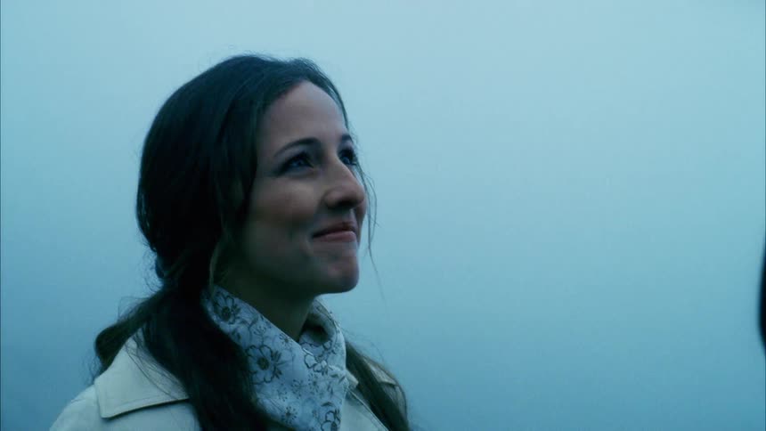 A woman standing with a man hugging her with fog in the background