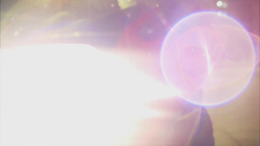 The headlight of a vehicle flickers before turning fully on outdoors at night