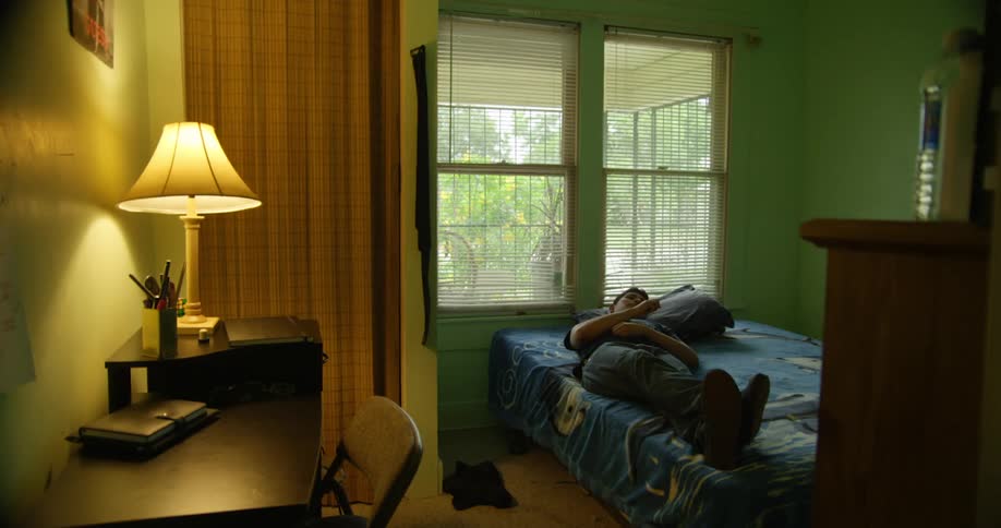 Man lies down on bed in his room