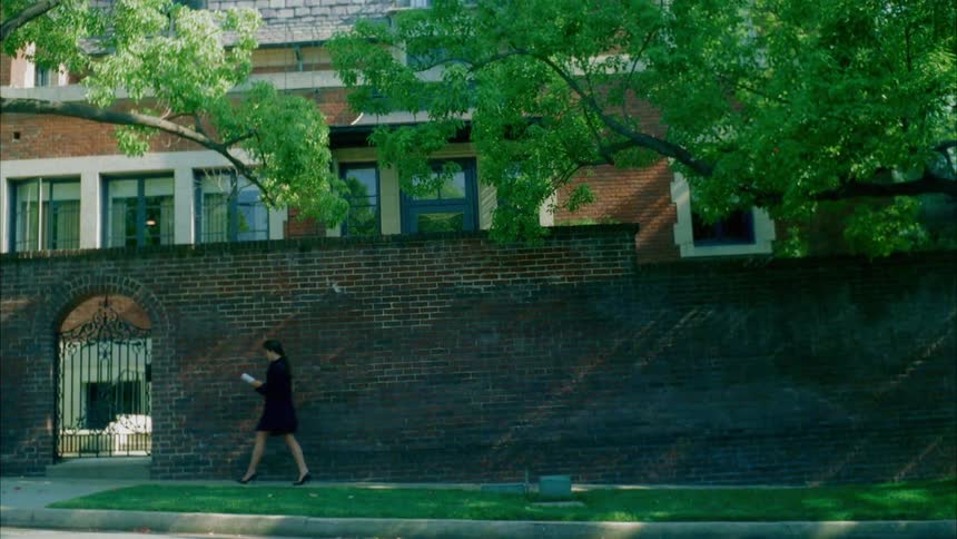 A woman walking down a sidewalk while reading