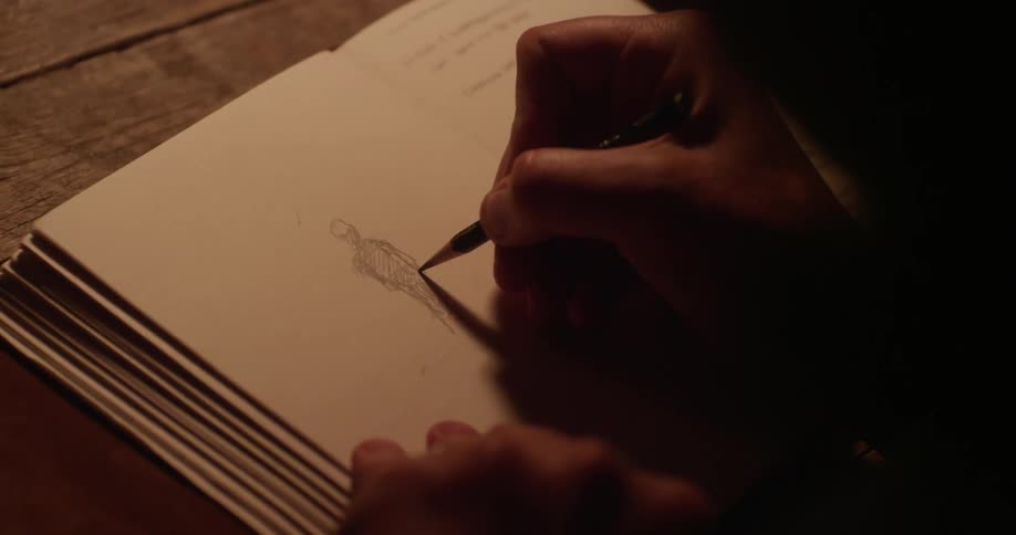 Person drawing a picture in a book in pencil