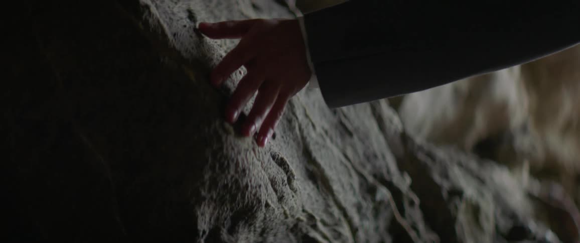 Someone is running their fingers across a rock cave wall