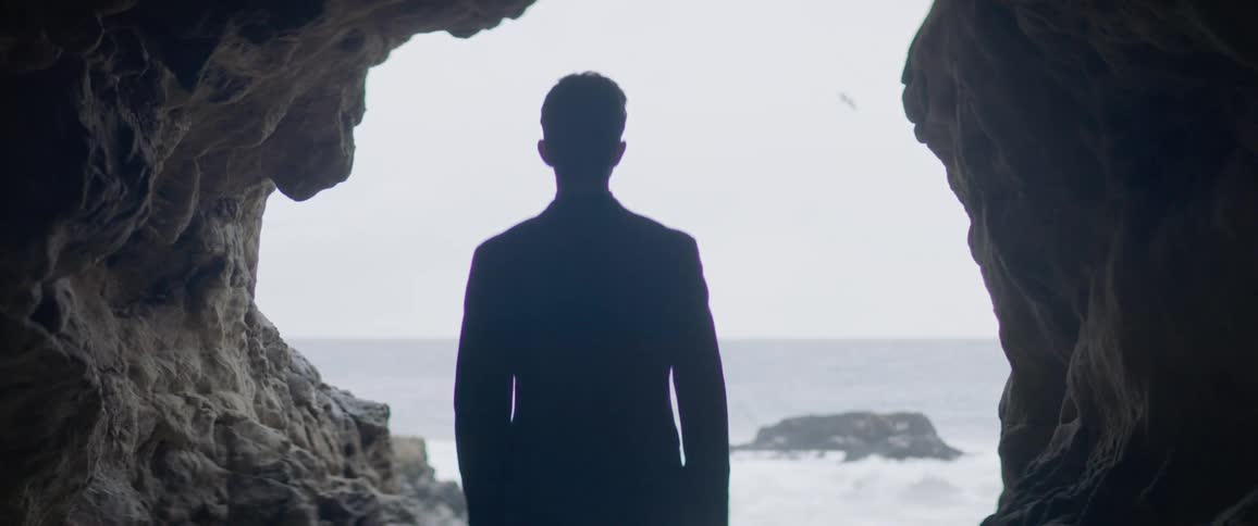 A man stands on a beach on a sunny day