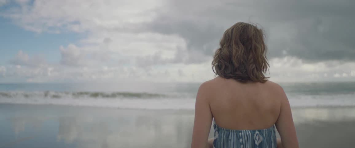 A woman walks towards the water of the beach