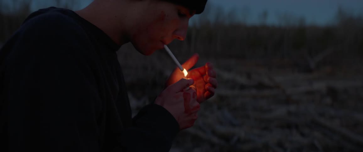 A young man lights a cigarette