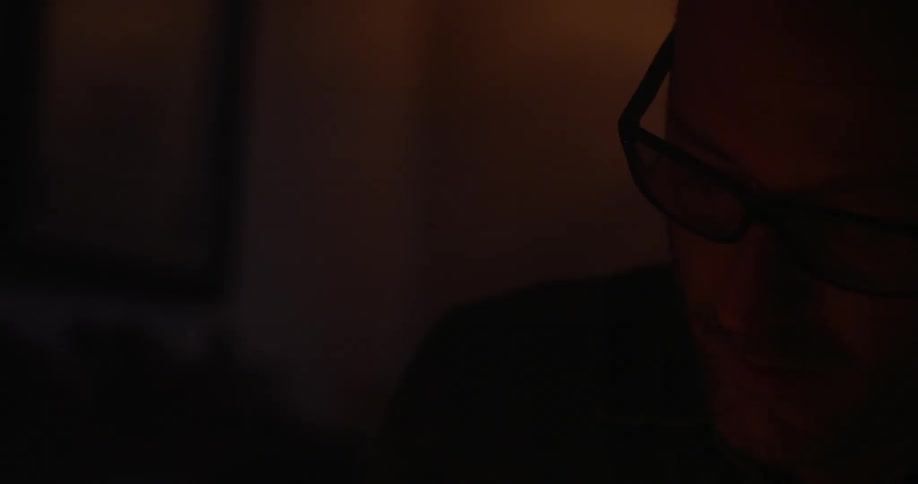 A man sits in a dim room