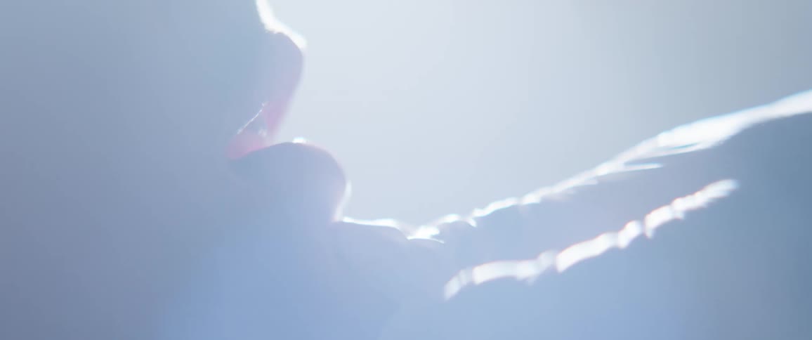A person shakes his head as a gloved hand tries to open his mouth