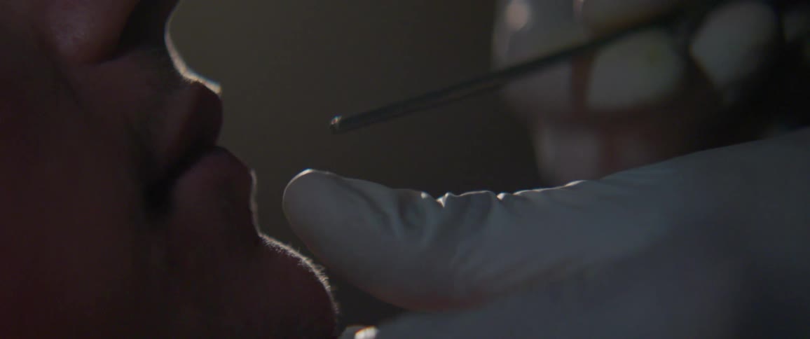 A doctor inserts a metal stick into someone's mouth