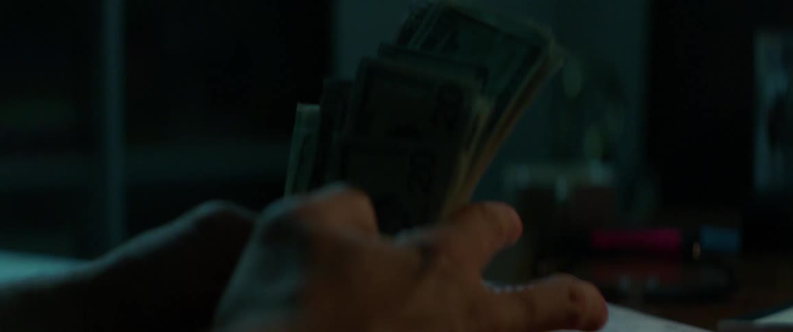 A person is counting a handful of twenty-dollar bills