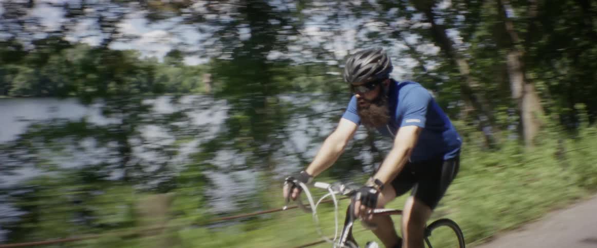 A man bicycles on a lakeside path