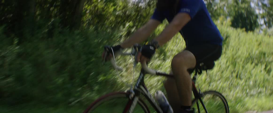A man is riding a bike down a road on a sunny day