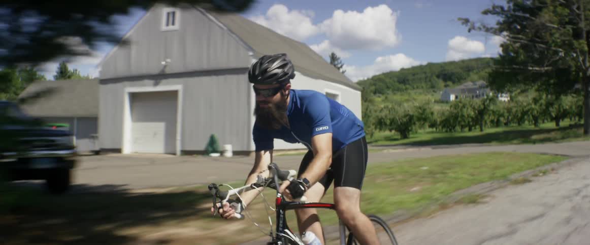 A man is riding his bike down a road on a sunny day