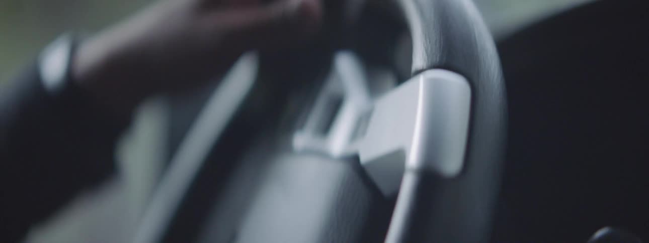 Close up of mans hands turning the steering wheel to control the direction of a vehicle