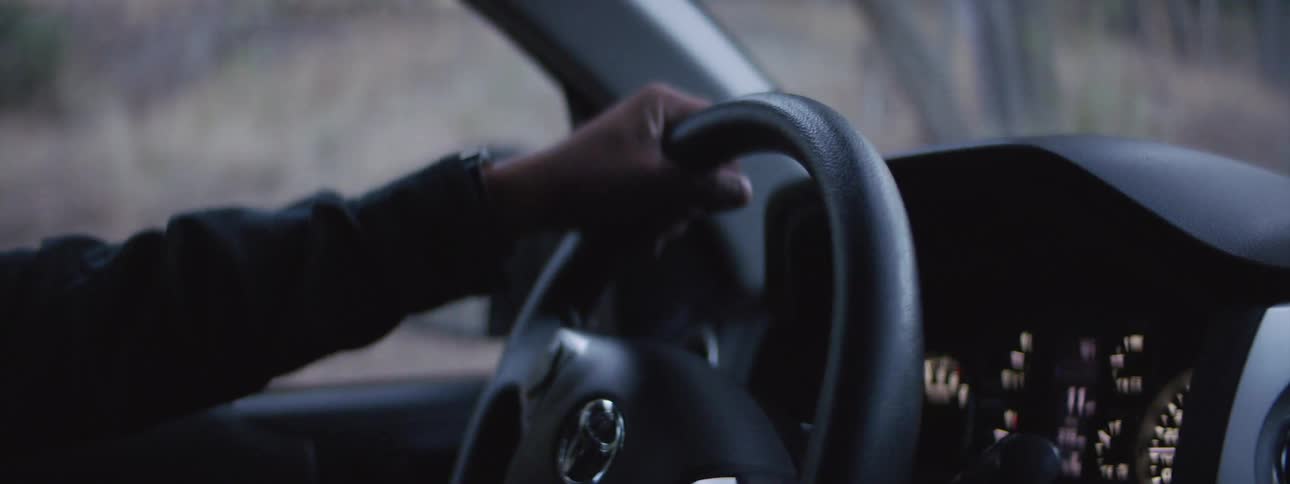 Man turns steering wheel to control the direction of a car