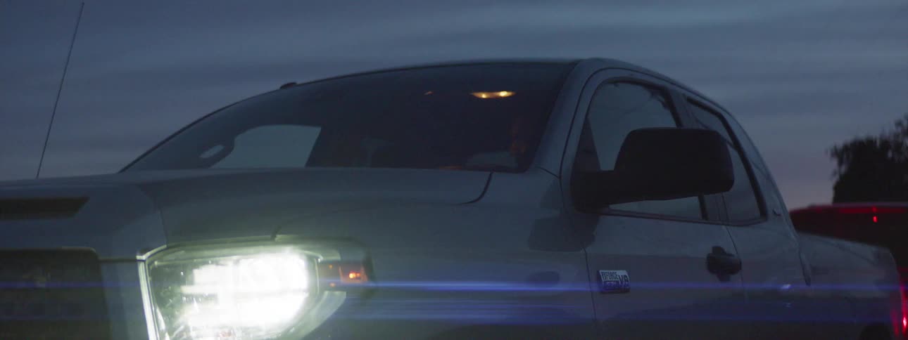 Man gets in a pickup truck and drives away at dusk