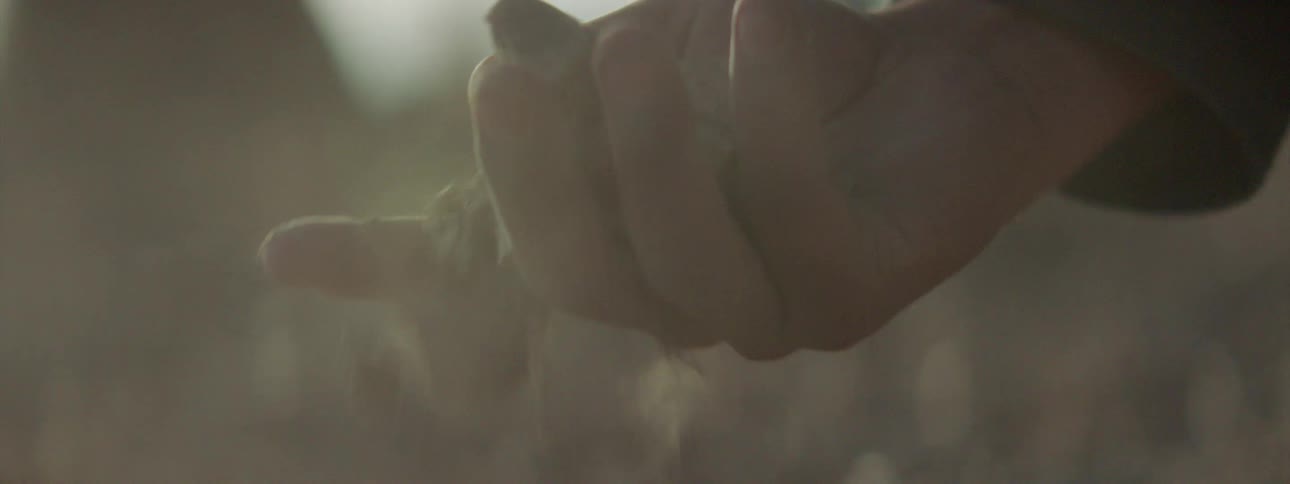 A hand picks up a rock and dirt and drops it back to the ground