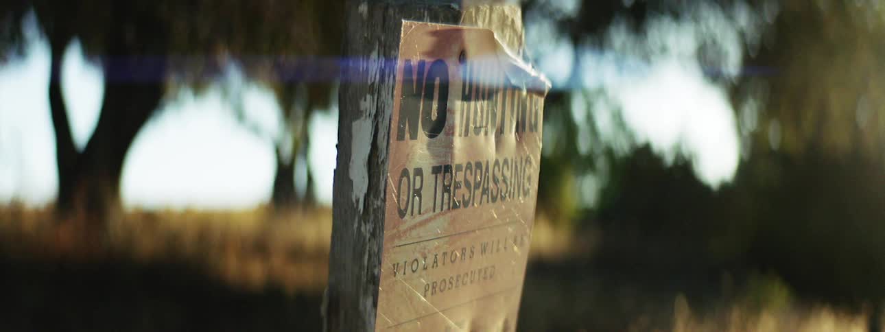 No trespassing or hunting sign on a grassy property