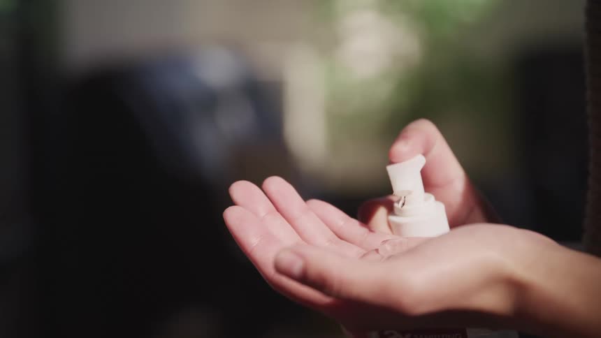 A person pumping hand sanitizer into the palm of their hand