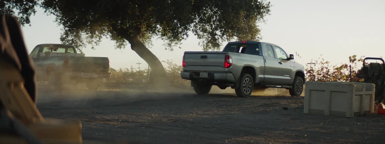 A truck pulls up and parks in a dirt lot