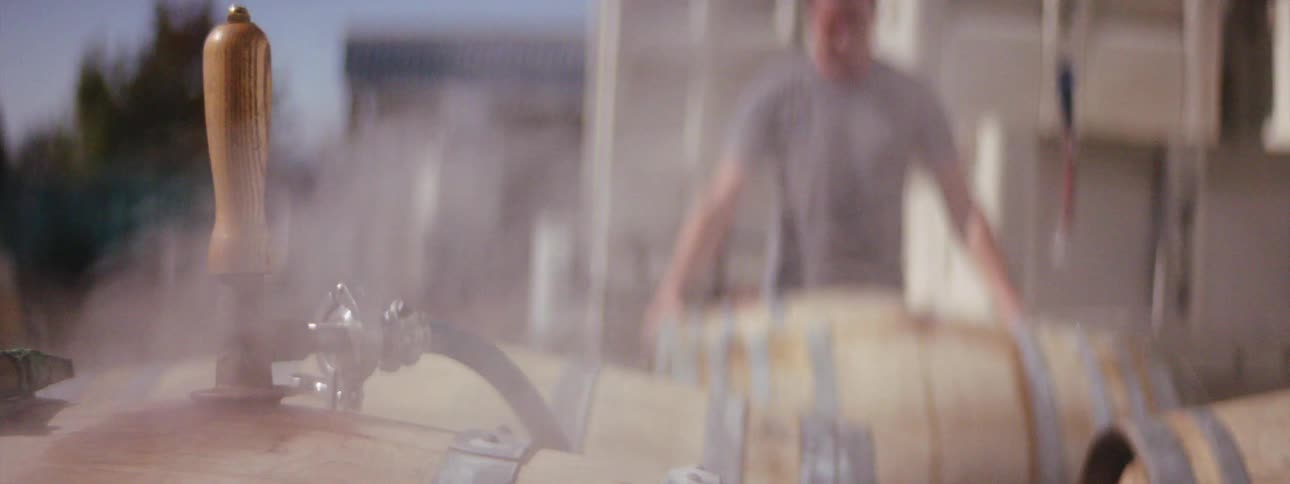 A man is stacking barrels in a parking lot