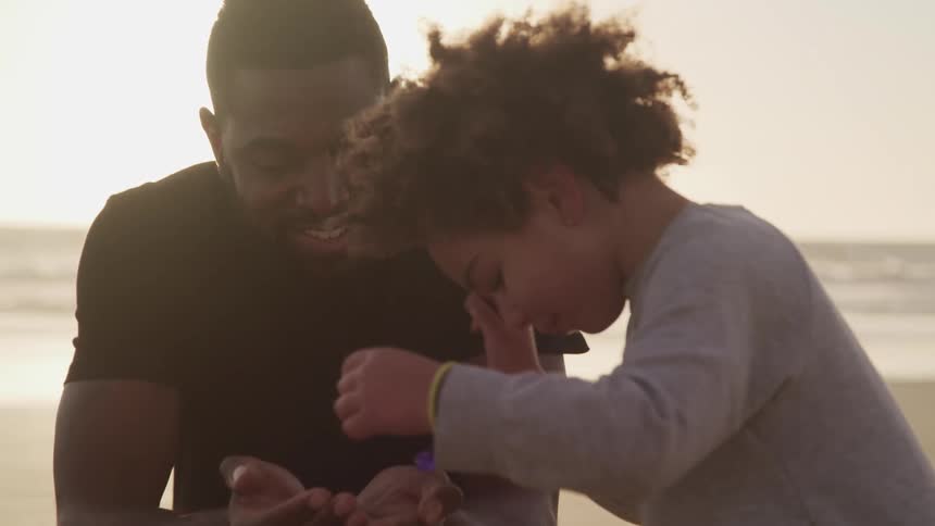 A child puts sand into a mans hands