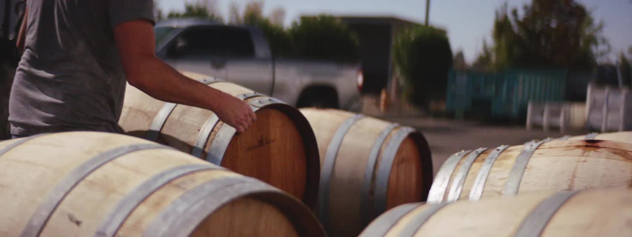 Man pushes a wooden barrel through the yard