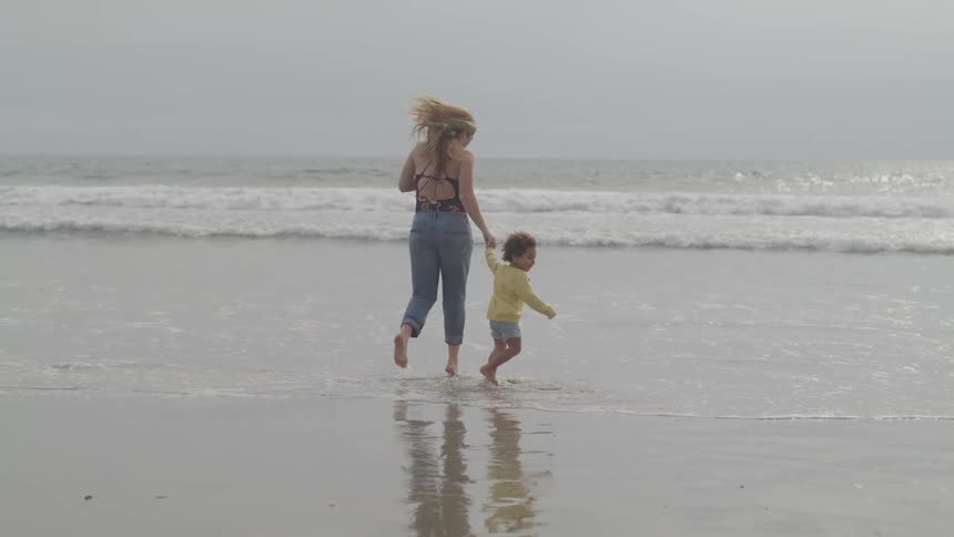 A mother and son run on the beach