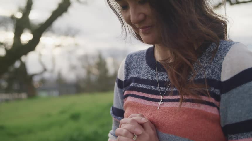 A woman stands outside and prays