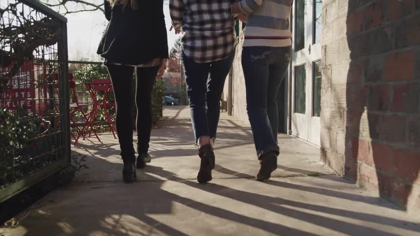 Three women walk down a sidewalk together