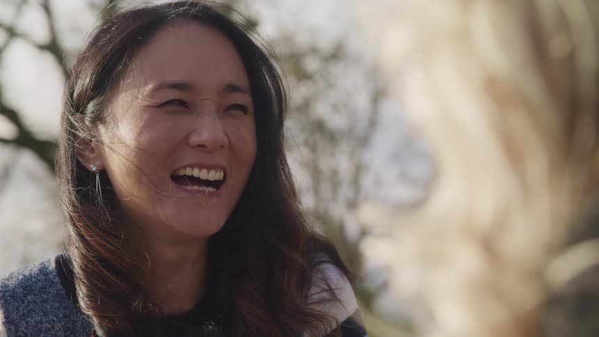 Asian woman with earrings and blonde white woman talk to each other and laugh together