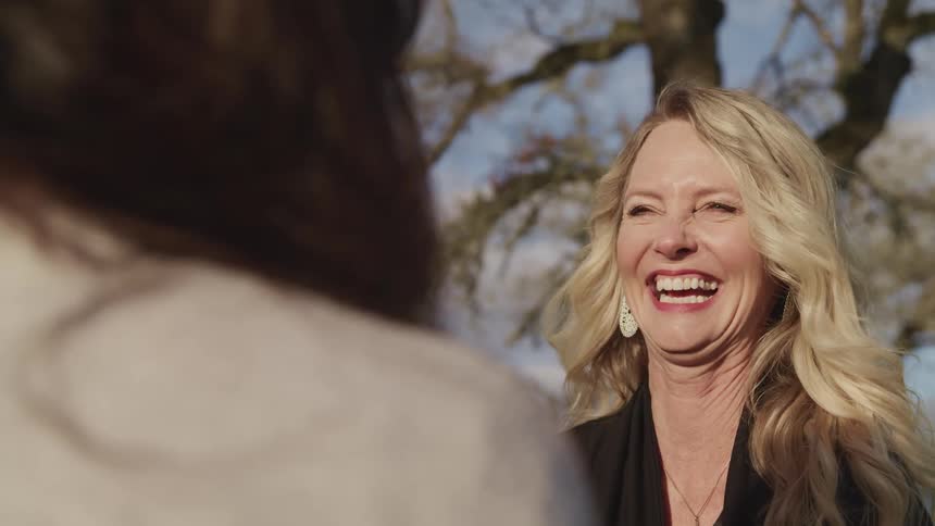 A woman laughs as she talks with a friend