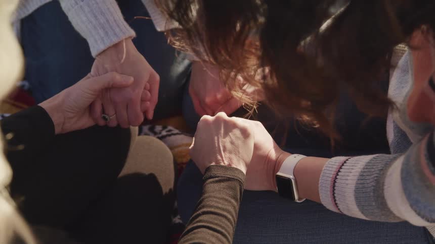 A group of friends are holding hands outside together