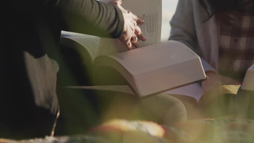 Two people sit together reading books