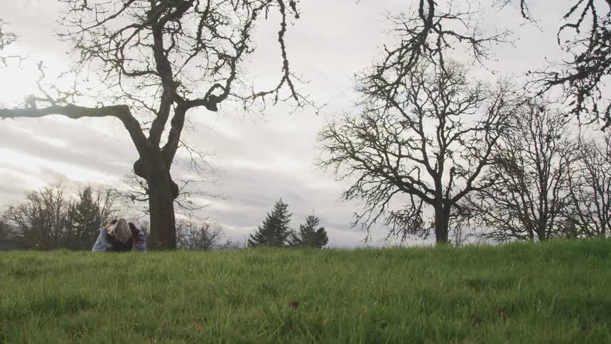 Three women sit by the tree in the grass