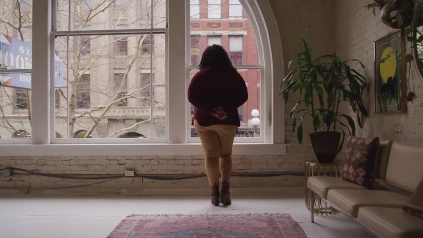A female standing in a building looking out the window