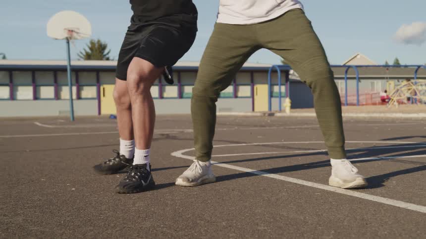 Two men are playing basketball in a public area basketball court