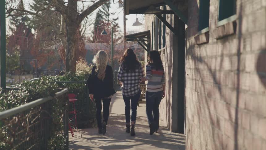 Three women walking together down a sidewalk