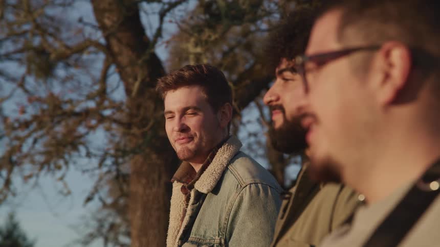 Three friends are sitting outdoors and smiling