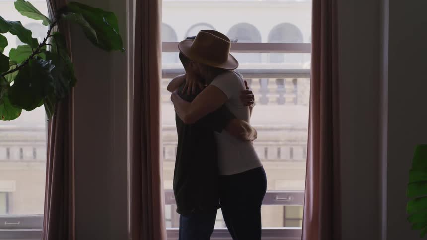 Two people hug by the window