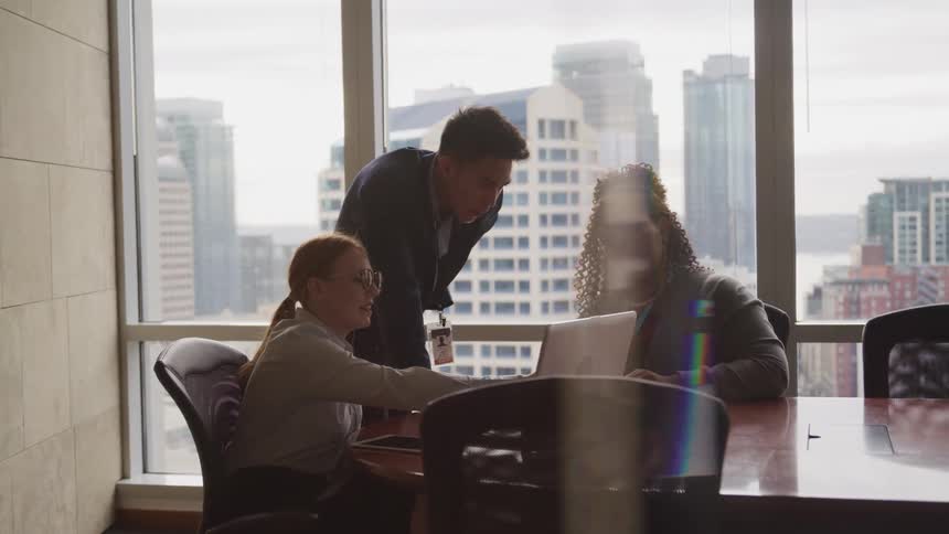 Three coworkers look at a laptop together