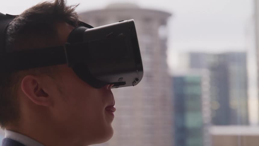 A man sticks his tongue out while using a virtual reality headset in his office