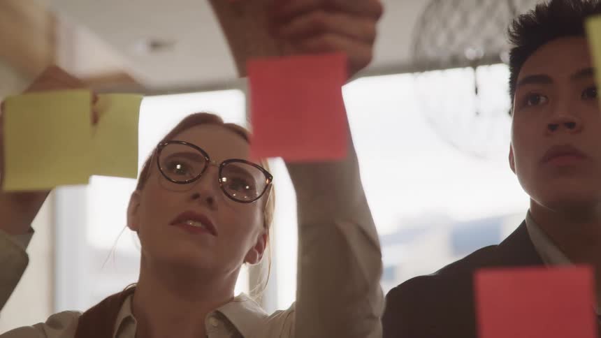 Caucasian female posting post its next to an asian male