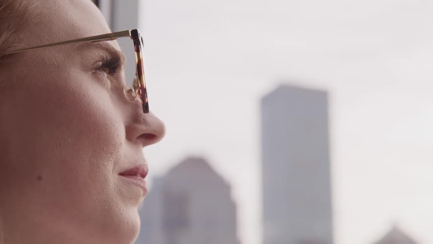 Woman wearing eye glasses blinks her eyes as she stands in a city