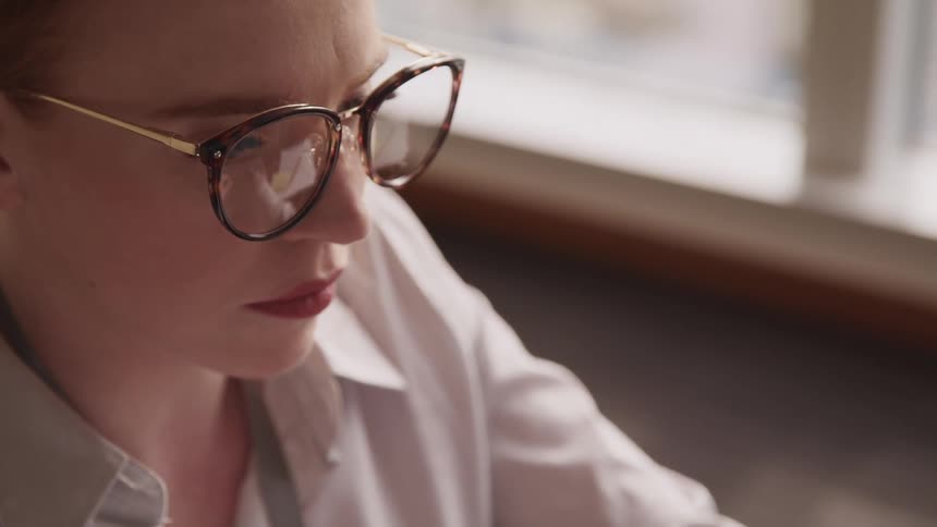 Side view of a businesswoman with red hair fair skin and glasses in an office