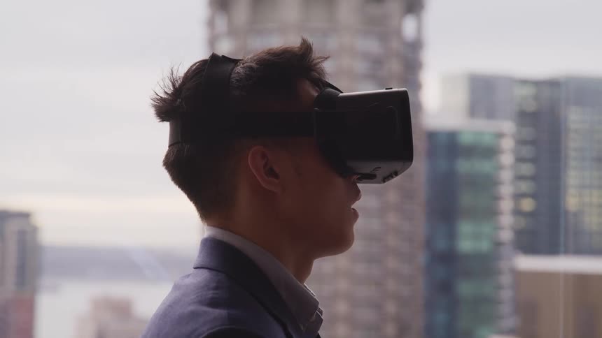 Man wearing virtual reality goggles standing in front of the city skyline