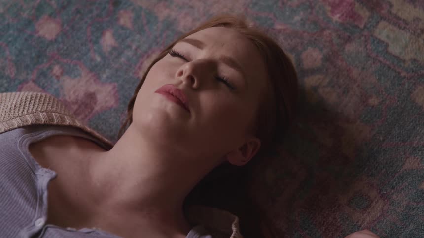 A woman laying on a carpet and closing her eyes