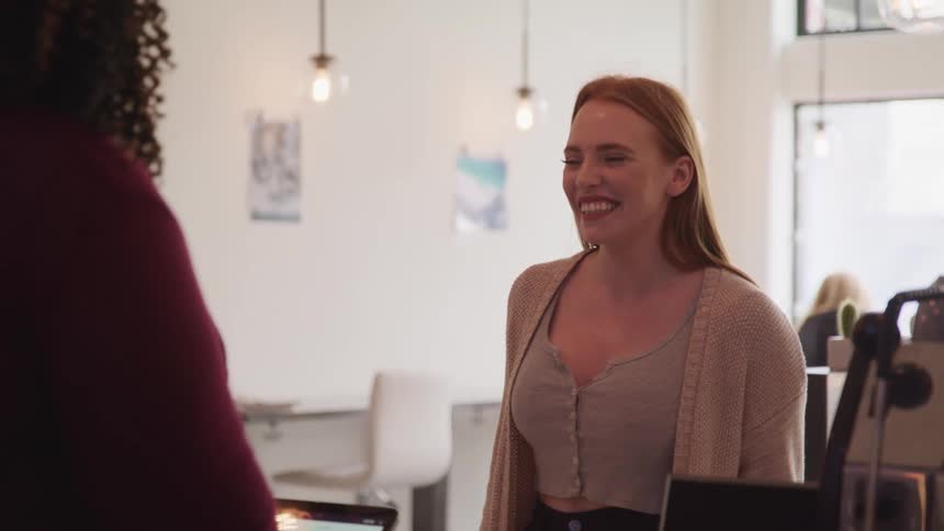 A woman talks with a cashier as she checks out