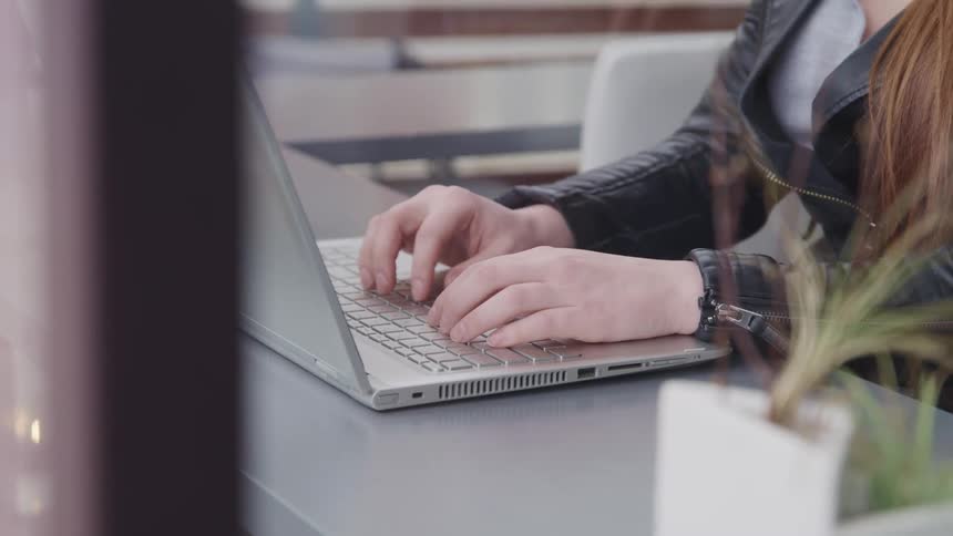 A young woman types on her laptop