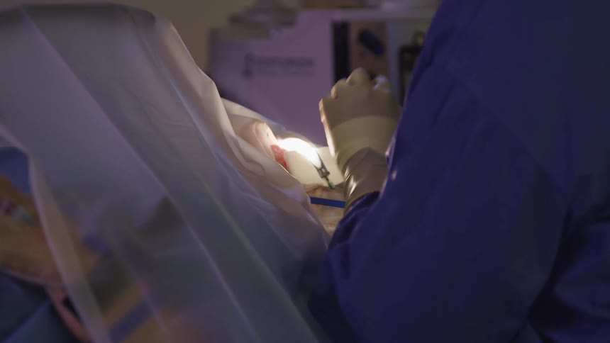 Person wearing scrubs and gloves gives patient an injection