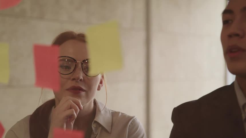 A man and woman look at sticky notes in an office